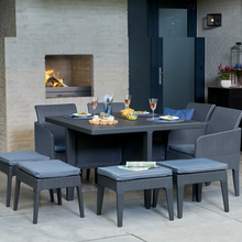 Load image into Gallery viewer, The Santiago 9 piece garden dining set with glasses of wine and plates laid out, with a fire burning in the background. 
