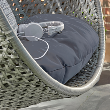 Load image into Gallery viewer, The Goldcoast single swing grey chair cushion and rattan effect detail. The cushion has some headphones.  
