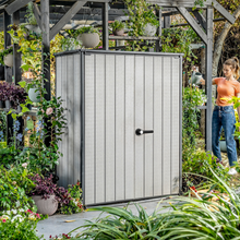 Load image into Gallery viewer, The Keter Hi-Store+ Storage Shed outside in the garden surrounded by plants and greenery.
