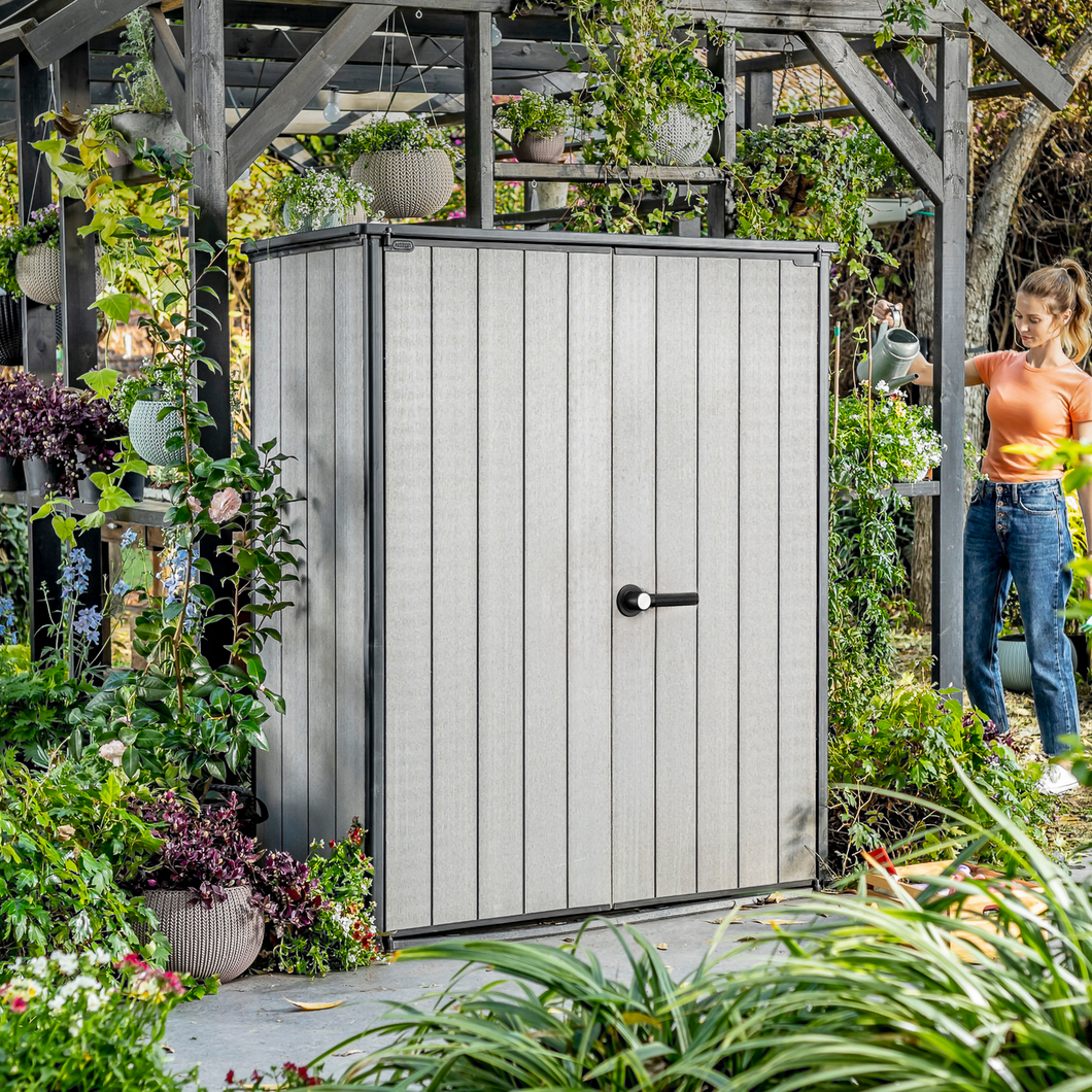 The Keter Hi-Store+ Storage Shed outside in the garden surrounded by plants and greenery.