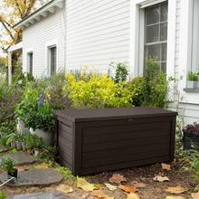 Load image into Gallery viewer, The Keter Hingham Storage Box 625L Dark Brown outside in the garden. 
