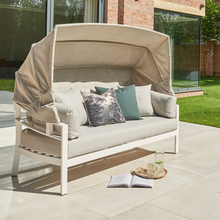 Load image into Gallery viewer, The Titchwell day bed on the garden patio with the canopy up to provide shade. 
