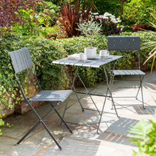 Load image into Gallery viewer, Courtyard Bistro Set out in the garden with a plant, two cups and a book on the table. 
