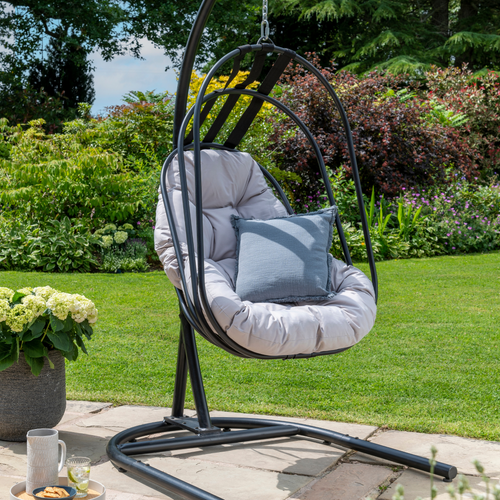 The folding basket swing chair in grey in the garden