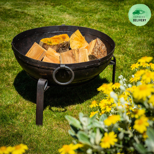 60cm fire pit in garden with wood inside and yellow flowers 