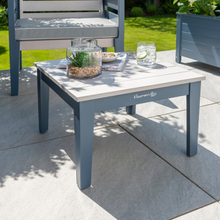 Load image into Gallery viewer, The Florenity Galaxy Side Table on the garden patio with a drink and magazine placed on the table top. The Florenity Galaxy chair is shown in the background. 
