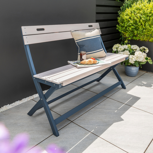 The Florenity Galaxy Folding Bench outside in the garden with a scatter cushion and food on the bench. 
