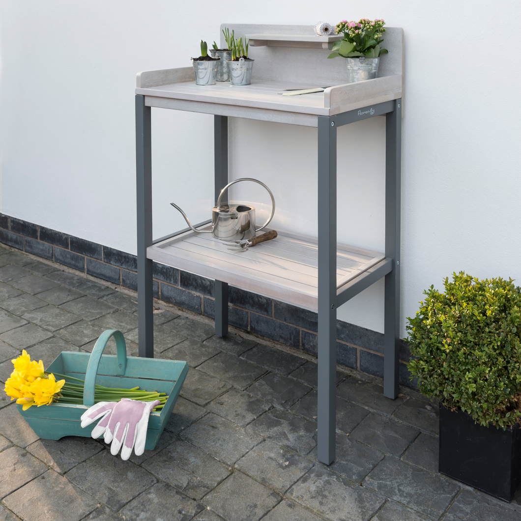 The Florenity Grigio Potting Table with some plants and a watering can on the shelves.