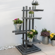 Load image into Gallery viewer, The Florenity Grigio Plant Stand with 5 plants on the various levels. The plant stand is outside on a garden patio. 

