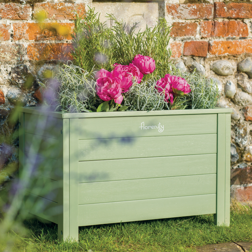 The Florenity Verdi Rectangular Planter stood against a wall with bright pink flowers planted inside. 