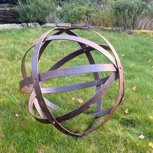 The 80cm rustic garden ball Sculpture outside in the garden on the grass. 