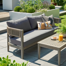 Load image into Gallery viewer, The arden rope sofa in the garden with some scatter cushions on.
