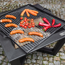 Load image into Gallery viewer, The Cook King square grill placed on a square fire pit. 
