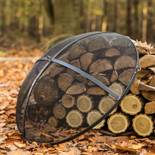 Load image into Gallery viewer, The Cook King fire pit mesh screen in the woods leant against some wooden logs
