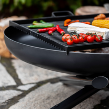 Load image into Gallery viewer, The Cook King square cooking grill with various foods on ready to cook. Showing the detail of the legs that stop the grill from moving. 
