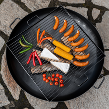 Load image into Gallery viewer, Overview of the cook king square cooking grill placed on a fire pit. The grill has a variety of food ready to be grilled. 
