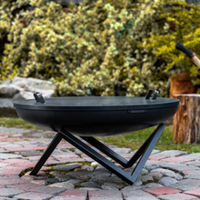 Load image into Gallery viewer, Fire Pit lid with two handles by Cook King on top of a fire pit outside in the garden. 
