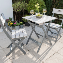 Load image into Gallery viewer, The Florenity Grigio Bistro Set in the garden. There are two glasses of wine and a bowl with pears inside on the table. 
