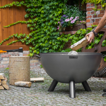 Load image into Gallery viewer, The Cook King Kongo firebowl outdoors with wood inside. 
