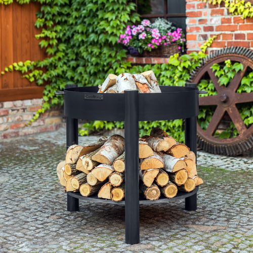 The Cook King Montana 80cm fire pit high in garden. The fire pit storage shelf has wood stored on it and within the fire pit bowl. 