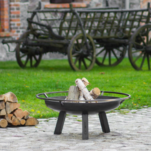 Load image into Gallery viewer, The Porto fire pit outside in the garden with some firewood inside. 
