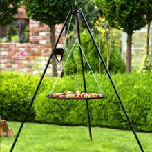 Load image into Gallery viewer, Cook King Black Steel Grate and Reel Tripod in garden. The black steel grate has various food items on. 
