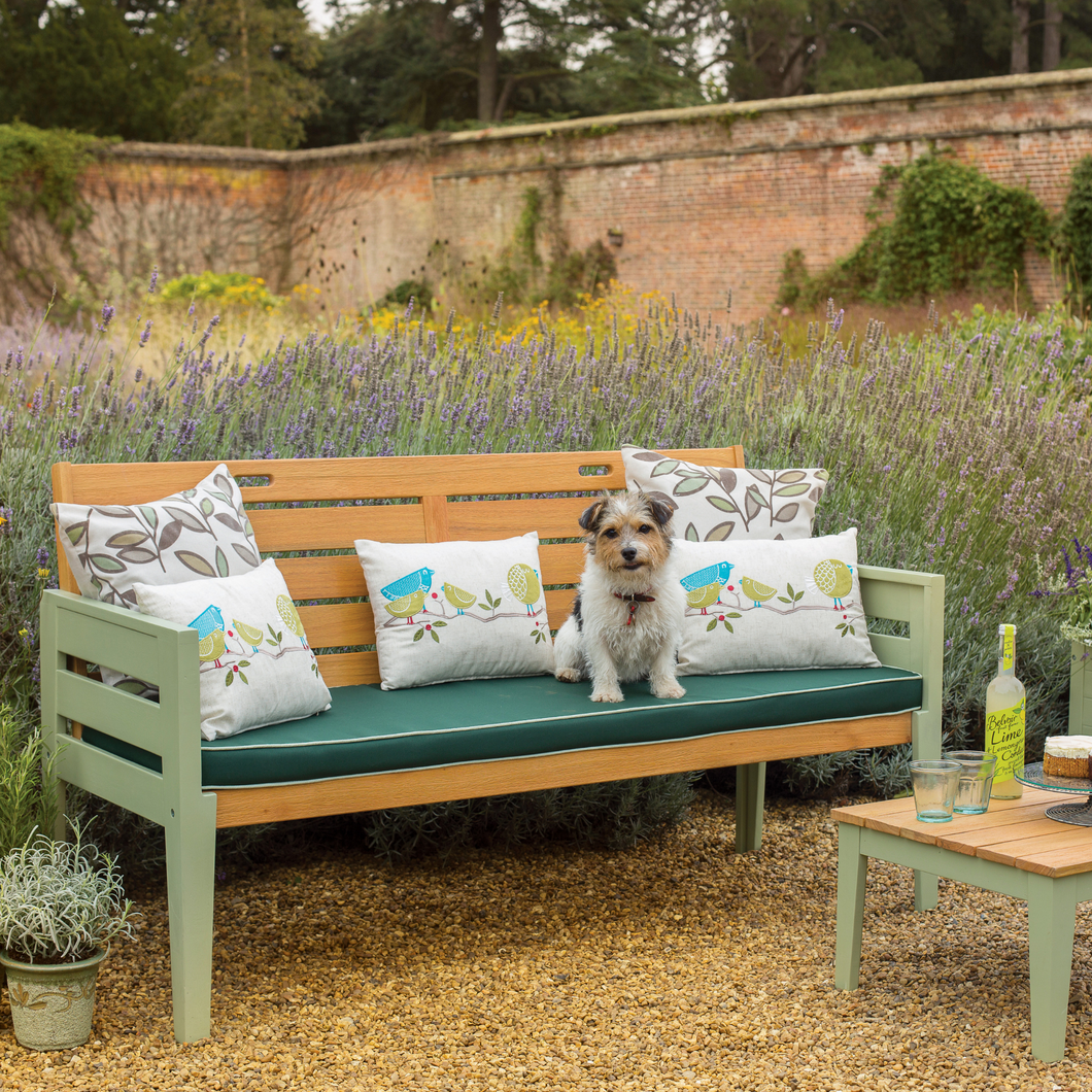 The Florenity Verdi three seat bench with a dog sat on it outside in the garden. 